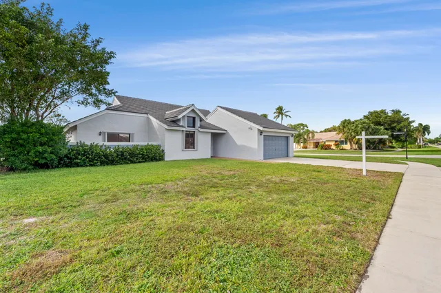 a front view of house with yard and trees in the background