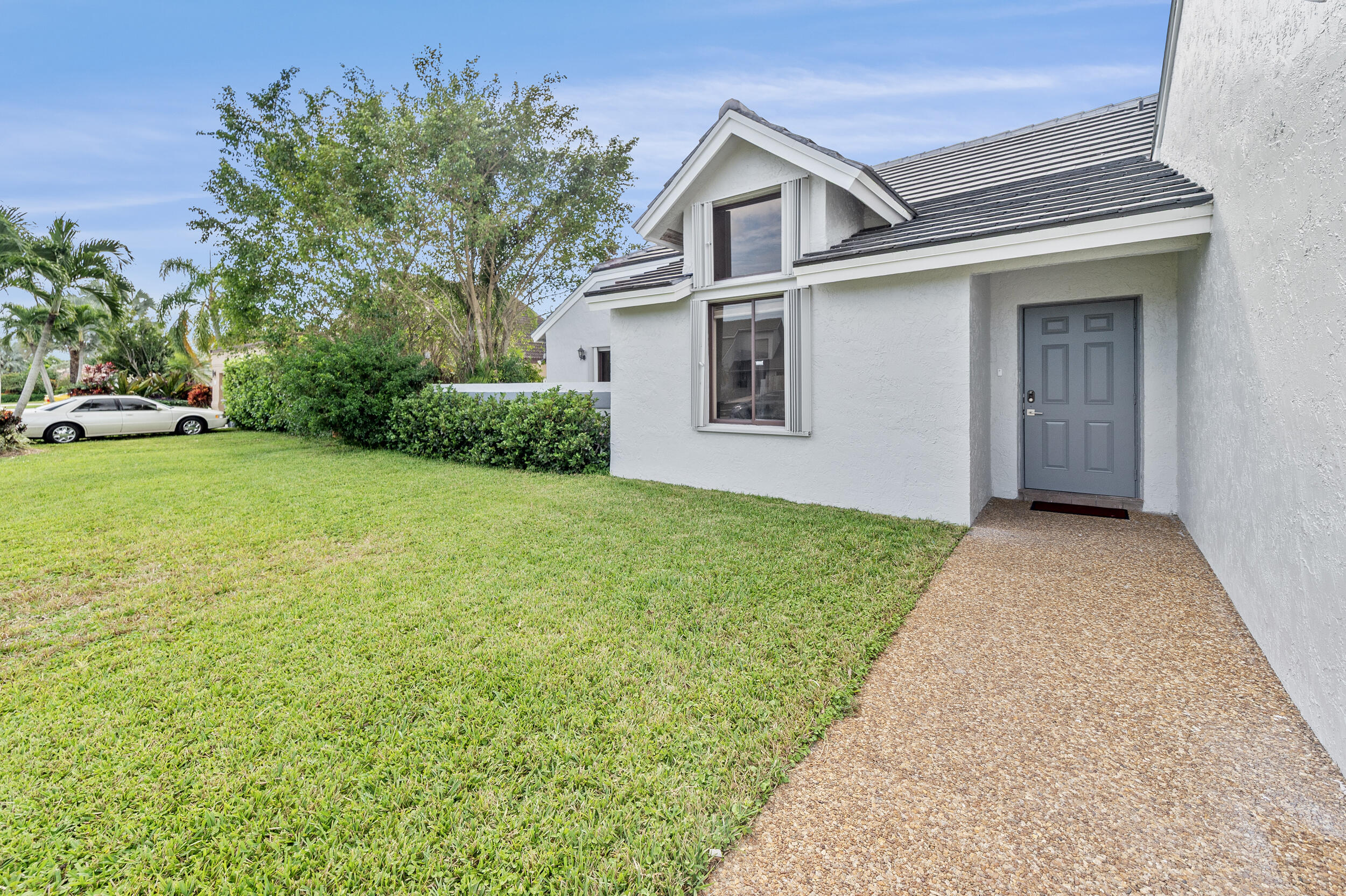 22301 Ensenada Way Boca Raton, FL 33433 - Photo 9 of 44 a view of a white house in front of a yard with plants and large tree