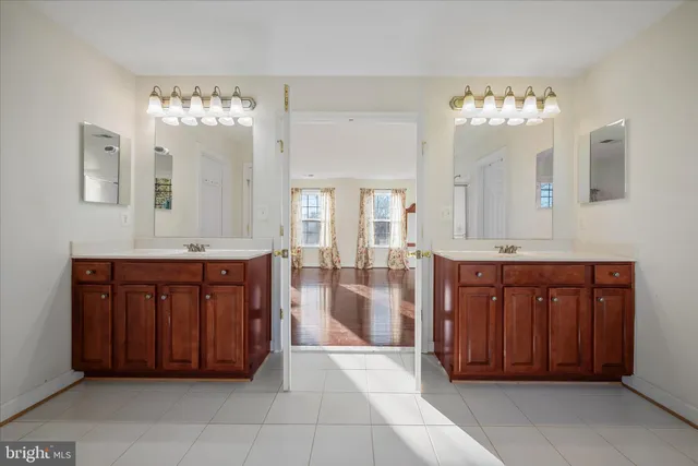 a spacious bathroom with a granite countertop double vanity sink a mirror and a bathtub