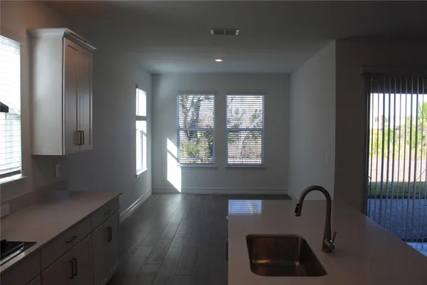 a kitchen with granite countertop a stove a sink a window and wooden floor