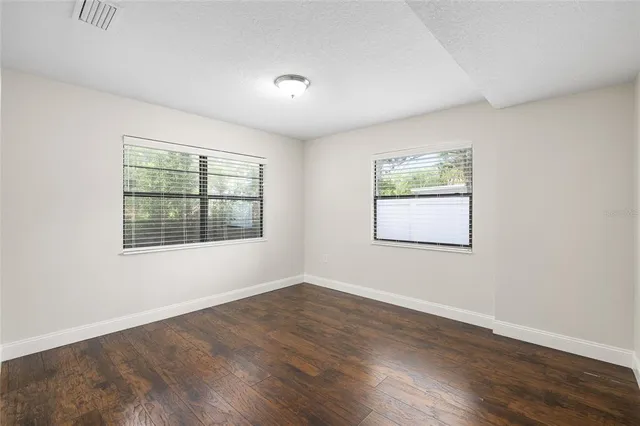 an empty room with wooden floor and windows