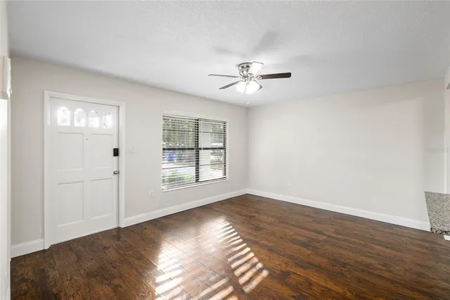 a view of an empty room with a window and wooden floor