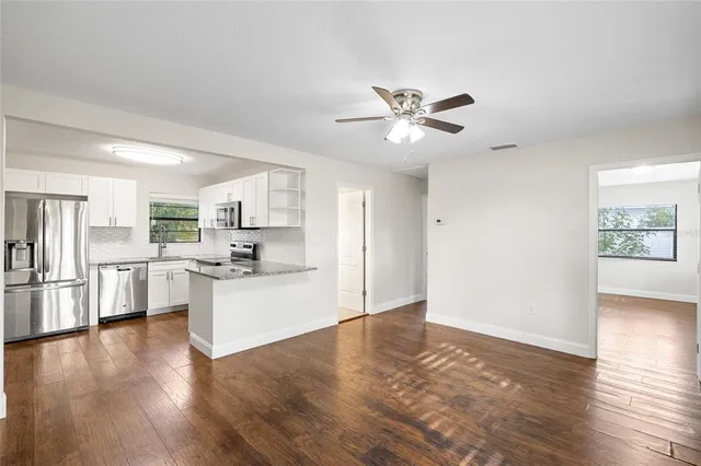 a view of kitchen with stainless steel appliances refrigerator a stove top oven with wooden floors