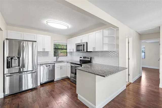 a kitchen with granite countertop a refrigerator and a stove top oven