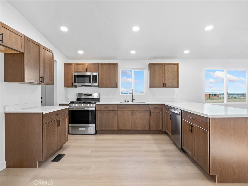 11623 Desert View Road Pinon Hills, CA 92372 - Photo 10 of 47 a large kitchen with stainless steel appliances granite countertop a stove top oven a sink dishwasher and a refrigerator with wooden cabinets