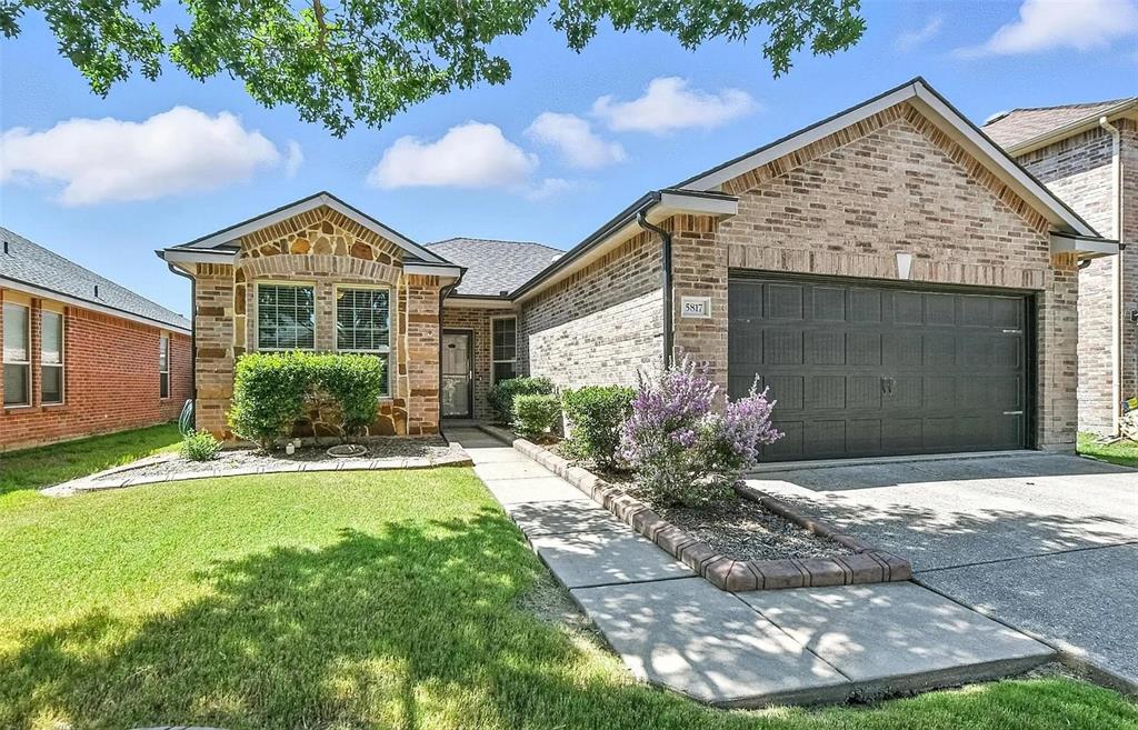 5817 Deck House Road Fort Worth, TX 76179 - Photo 1 of 19 Brick and stone facade residence featuring a two-car garage, a concrete driveway, a front lawn, a paved walkway, and maintained landscaping