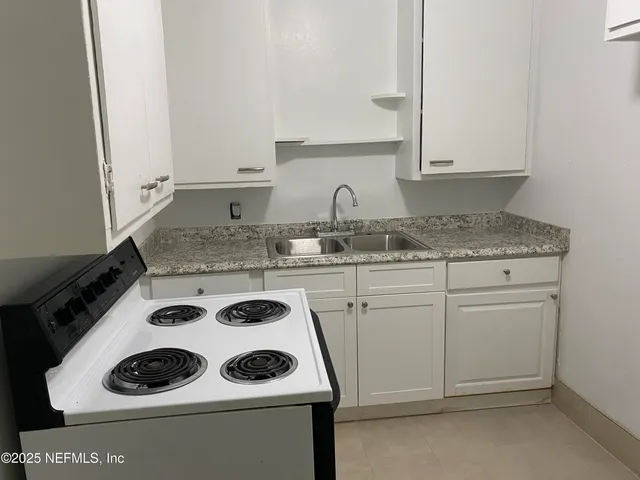 a kitchen with a sink a stove and cabinets