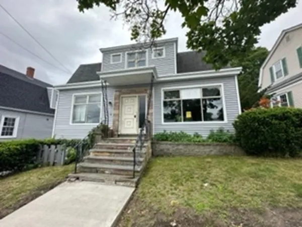 a view of a white house with large windows and a yard with plants and large trees