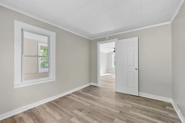 a view of an empty room with wooden floor and a window