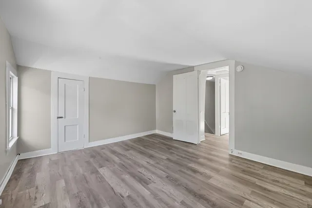a view of an empty room with wooden floor and window