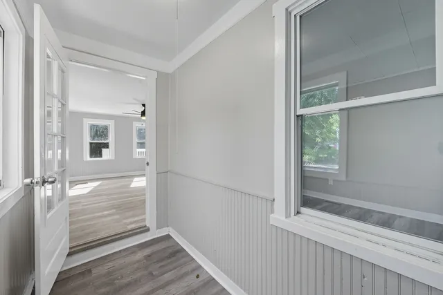 a view of an empty room with wooden floor and a window