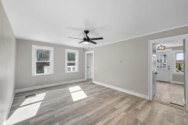 a view of empty room with wooden floor and fan