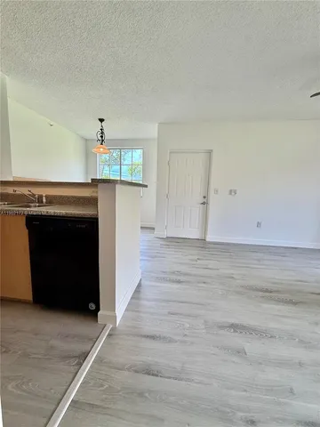 a view of an empty room with wooden floor and a fireplace