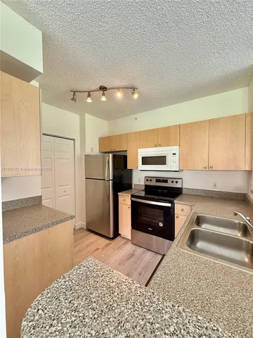 a kitchen with granite countertop a refrigerator and a sink