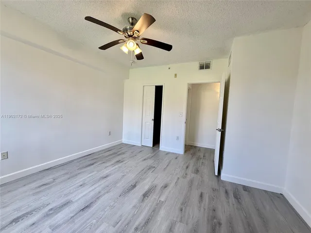 an empty room with wooden floor and ceiling fan