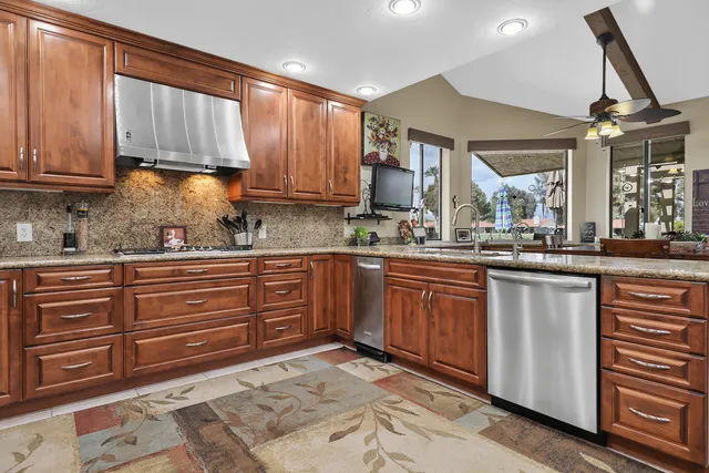 a kitchen with granite countertop wooden cabinets stainless steel appliances a sink and a window