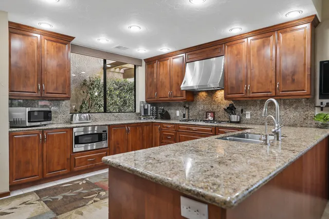 a kitchen with granite countertop a sink a counter space appliances and cabinets
