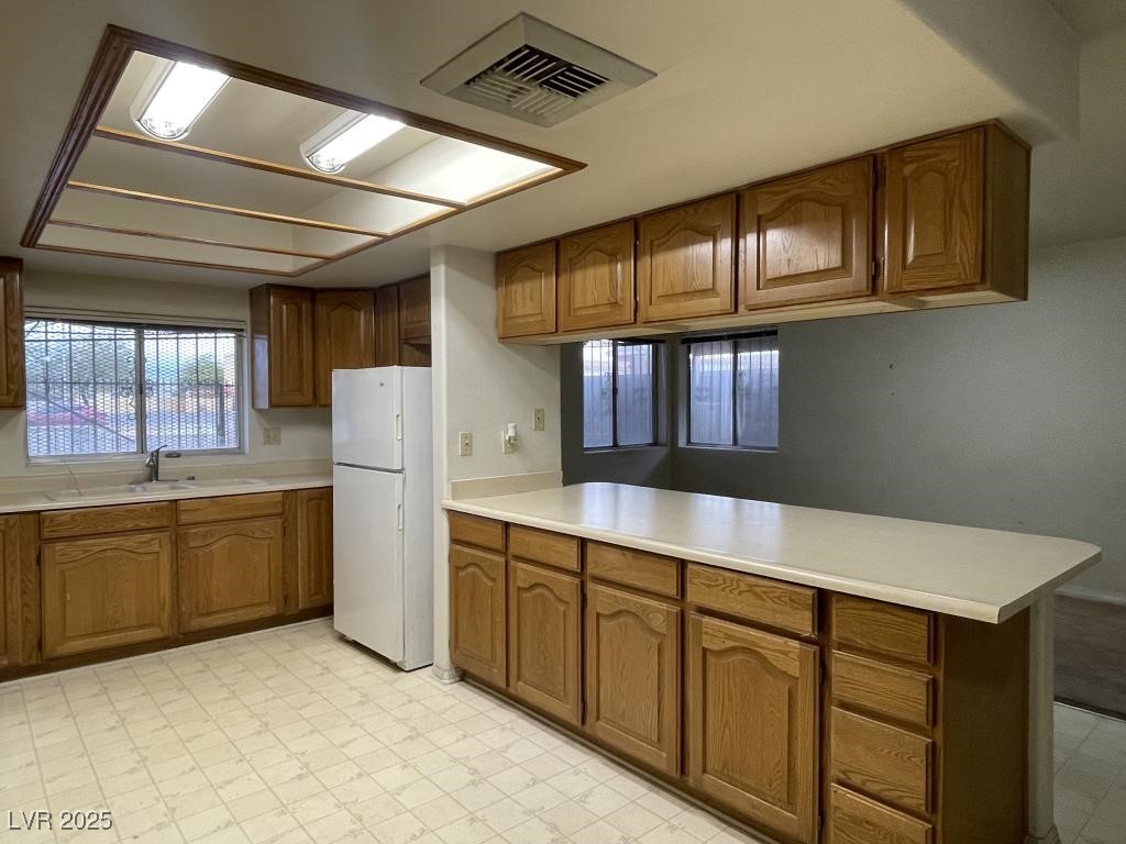 3530 North Pecos Road Las Vegas, NV 89115 - Photo 23 of 46 Kitchen featuring visible vents, freestanding refrigerator, a peninsula, light floors, and a sink