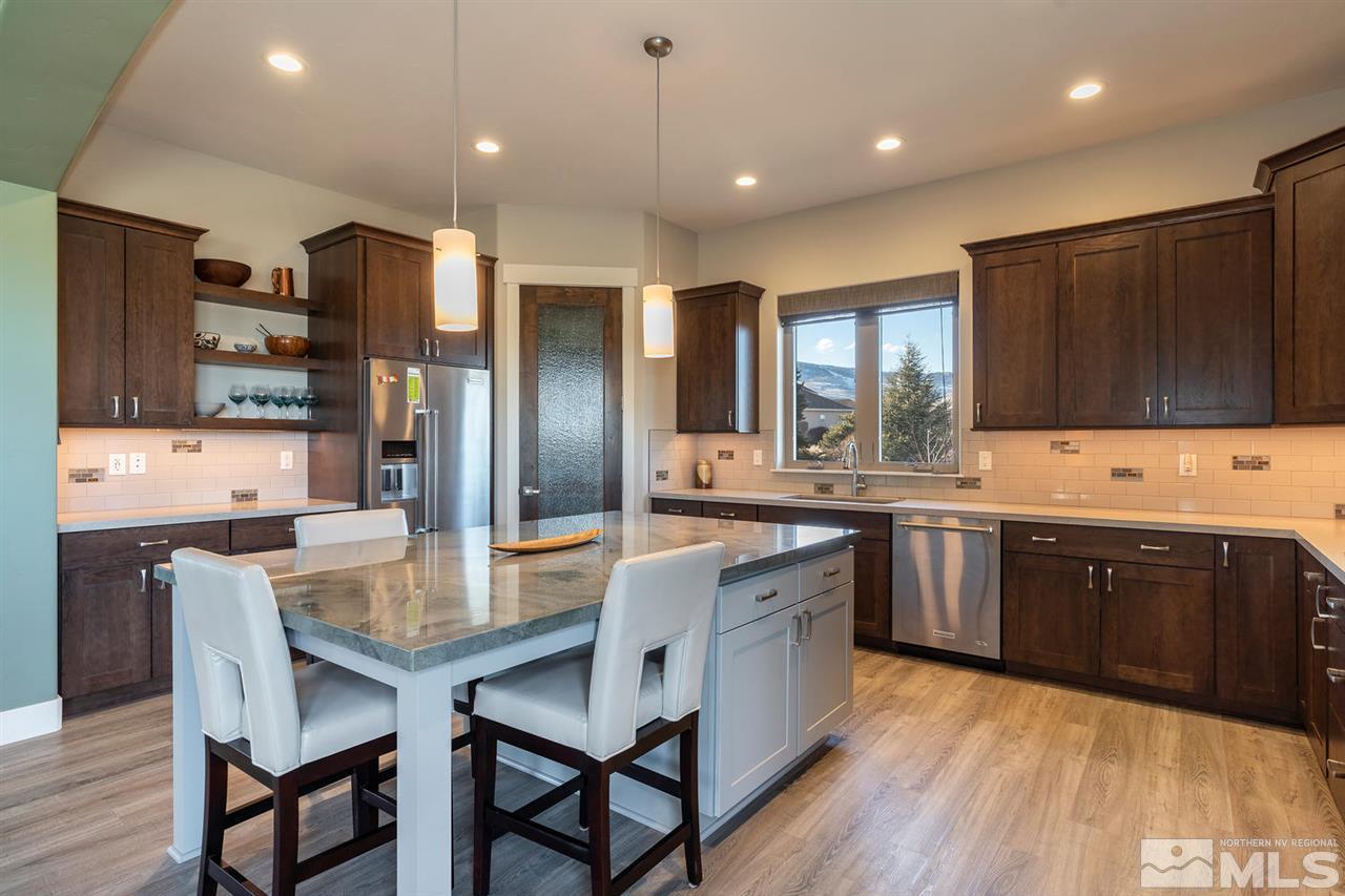 4920 Gila Bend Road Reno, NV 89511 - Photo 8 of 23 a large kitchen with granite countertop a dining table chairs wooden cabinets and stainless steel appliances