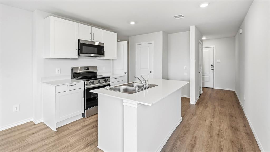 3535 Spring Time Street Forney, TX 75126 - Photo 2 of 23 Contemporary kitchen featuring white cabinetry, a stainless steel appliance suite, and light wood-finish flooring