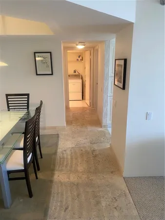 a view of a hallway to a livingroom with furniture and a window