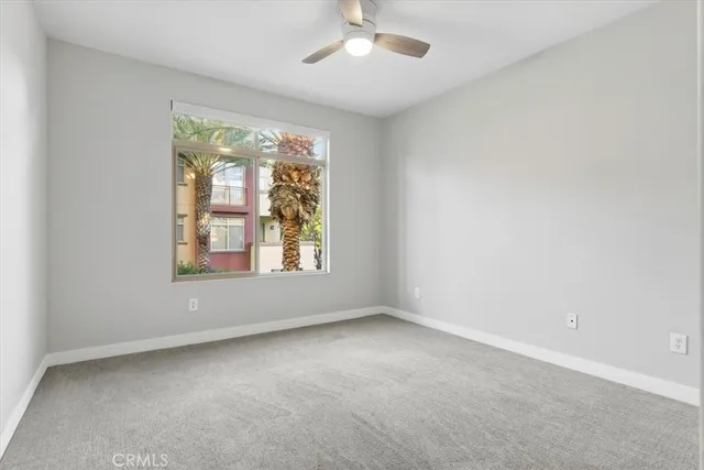 an empty room with windows and chandelier fan
