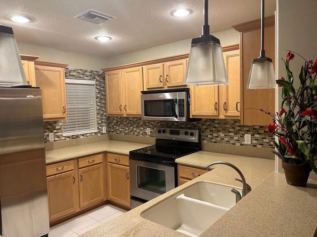 8807 White Sage Loop Lakewood Ranch, FL 34202 - Photo 3 of 19 a kitchen with granite countertop a stove a sink and a microwave