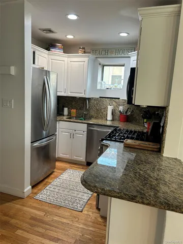 a kitchen with kitchen island granite countertop a sink appliances and cabinets