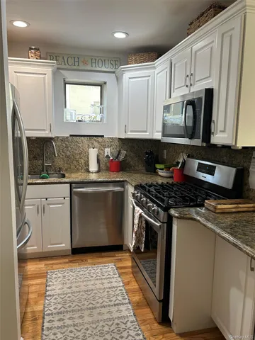 a kitchen with stainless steel appliances granite countertop a stove a sink and a microwave