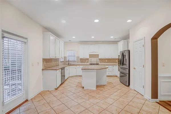 a kitchen with stainless steel appliances kitchen island granite countertop a refrigerator and a sink