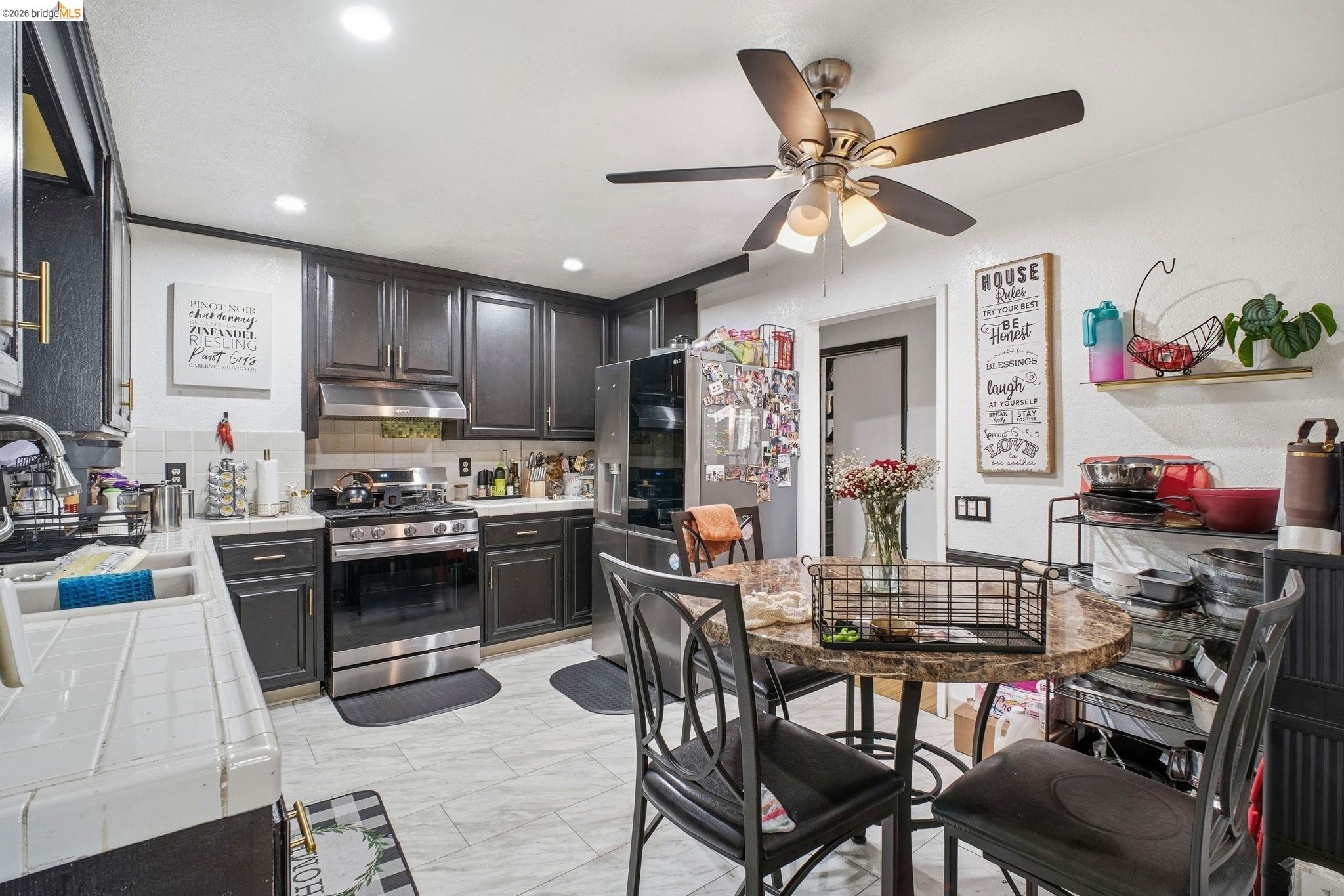 127 Hampton Road Hayward, CA 94541 - Photo 7 of 22 Kitchen with tile counters, appliances with stainless steel finishes, tasteful backsplash, under cabinet range hood, and a ceiling fan