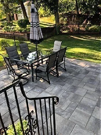 a view of a chair and tables in the yard and large trees