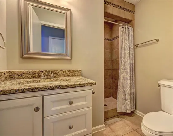 a bathroom with a granite countertop sink toilet and shower