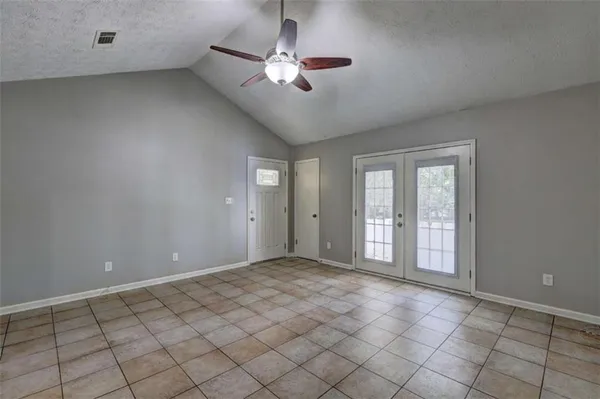 an empty room with chandelier fan and windows