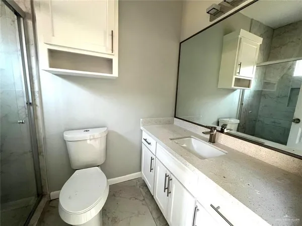 a bathroom with a granite countertop toilet sink and mirror