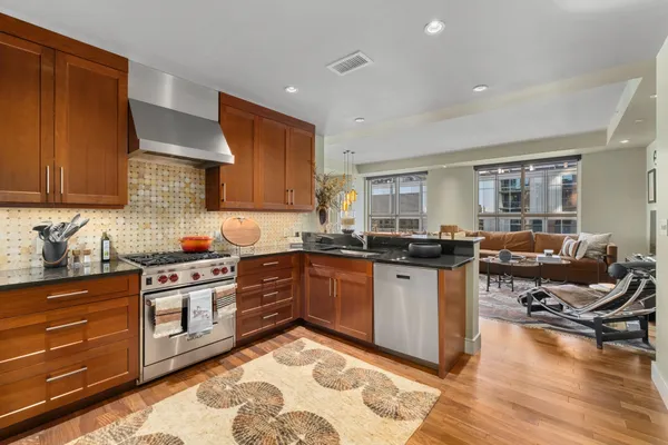 a kitchen with stainless steel appliances granite countertop a stove top oven a sink dishwasher and cabinets with wooden floor