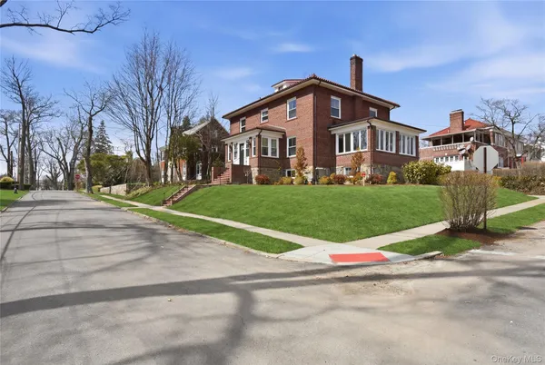 a view of a white house with a yard and large trees