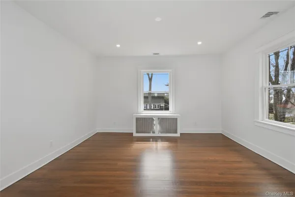 a view of empty room with wooden floor and window