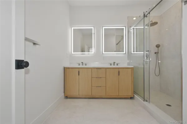 a bathroom with a double vanity sink a mirror and shower