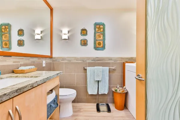 a bathroom with a granite countertop toilet sink and mirror