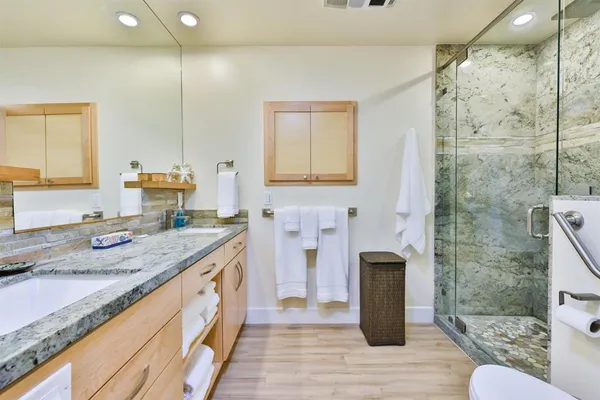 a bathroom with a granite countertop sink a toilet and shower