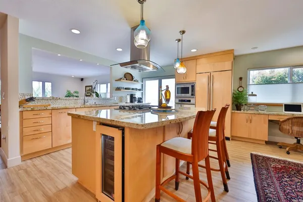 a kitchen with stainless steel appliances kitchen island granite countertop a table chairs sink and cabinets