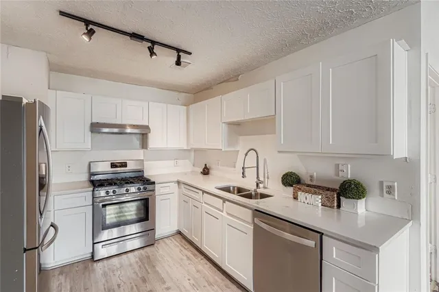a kitchen with granite countertop a sink stainless steel appliances and cabinets