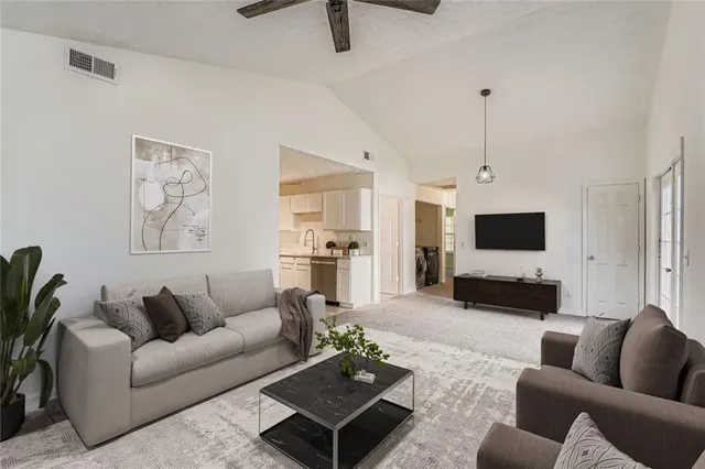 a living room with furniture kitchen view and a wooden floor