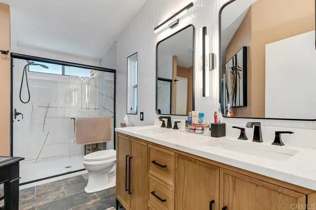 a bathroom with a double vanity sink toilet mirror and shower