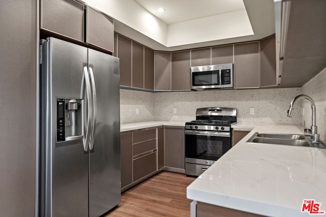 3618 Dunn Drive, Unit 304 Los Angeles, CA 90034 - Photo 2 of 13 a kitchen with stainless steel appliances kitchen island a refrigerator sink and microwave