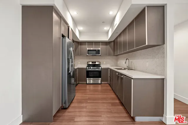 a kitchen with stainless steel appliances granite countertop a refrigerator a sink and wooden cabinets