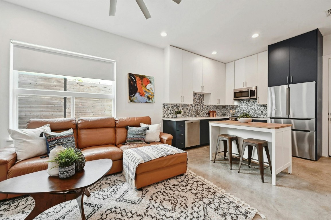 a living room with stainless steel appliances kitchen island granite countertop furniture and a large window