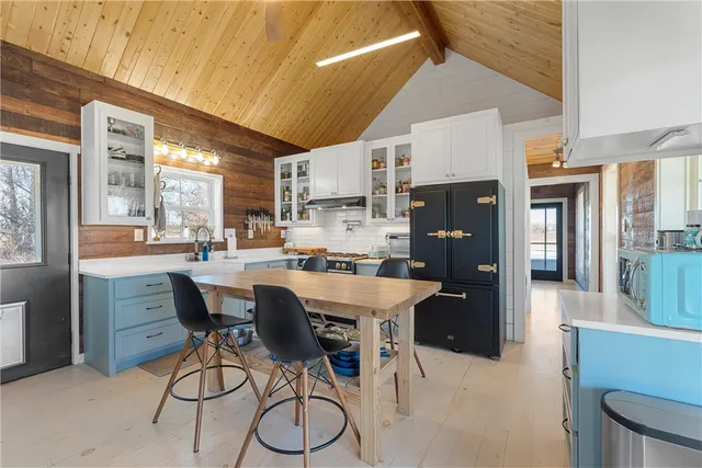 a dining hall with stainless steel appliances kitchen island granite countertop a dining table chairs and a refrigerator