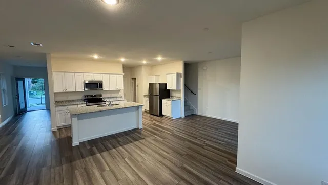 a kitchen with granite countertop white cabinets and wooden floor